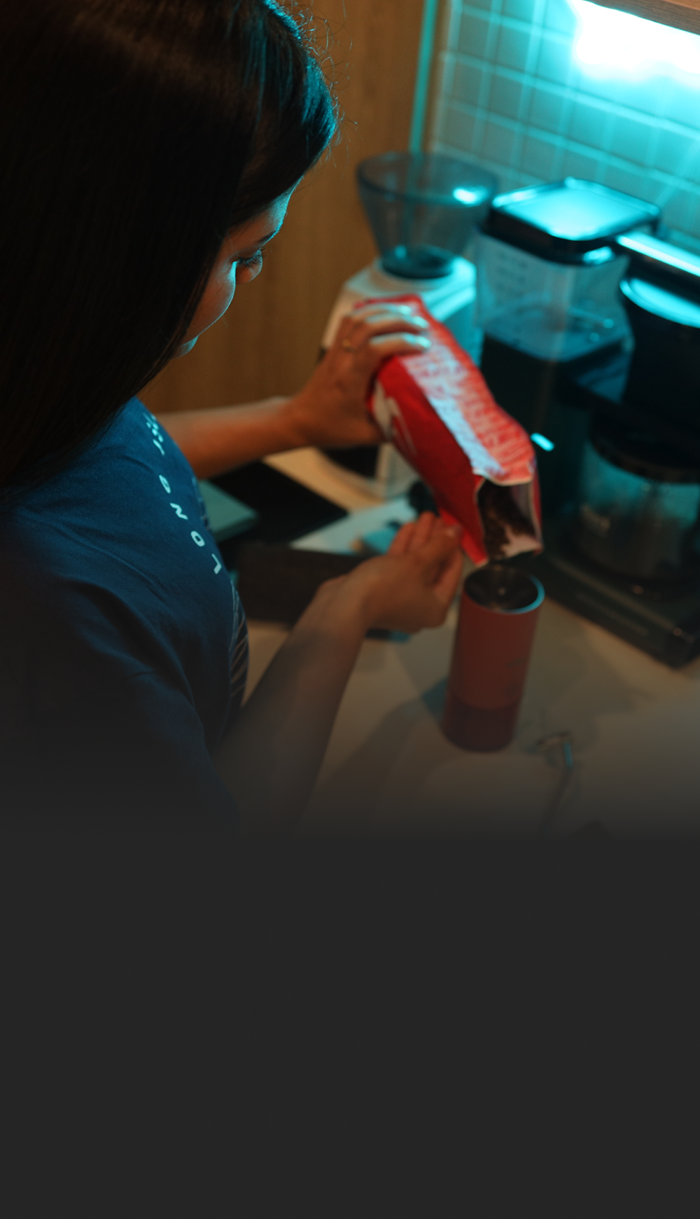 mujer echando café de la marca raro en un molino manual